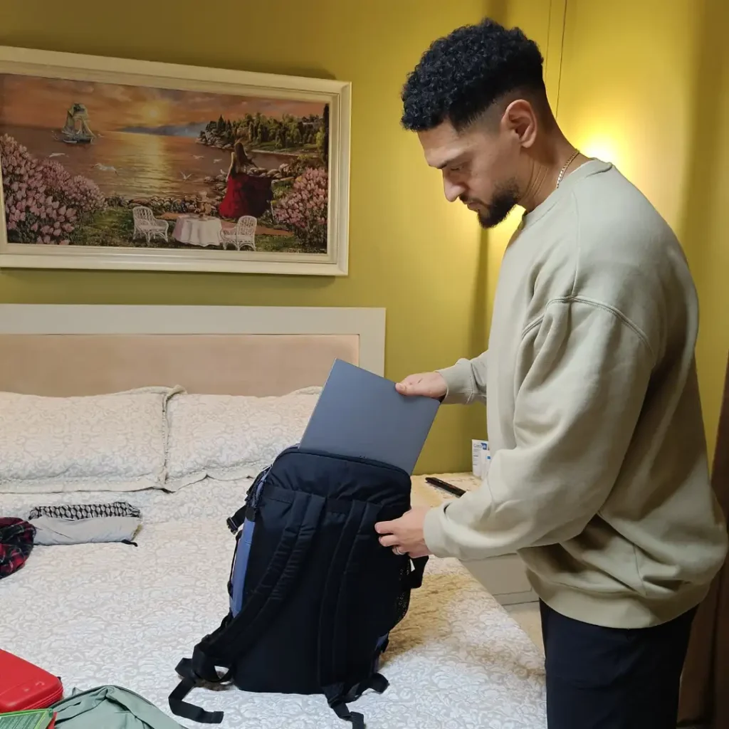 A 15.6 inch laptop being placed into the Eastpak Carry Pack laptop compartment